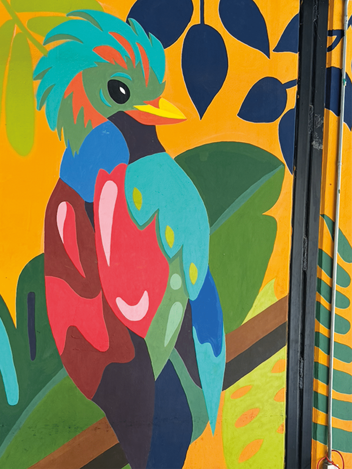 A colorful bird is perched on a branch in front of a yellow wall. Contenido generado con IA