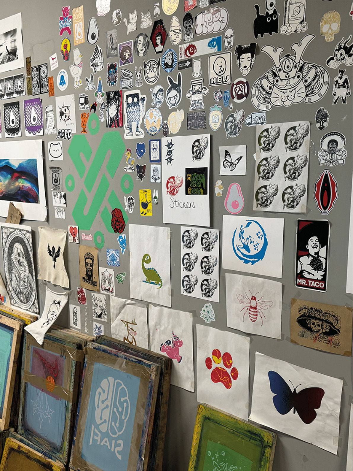A wall filled with various stickers and posters, including a sticker of a butterfly. Contenido generado con IA