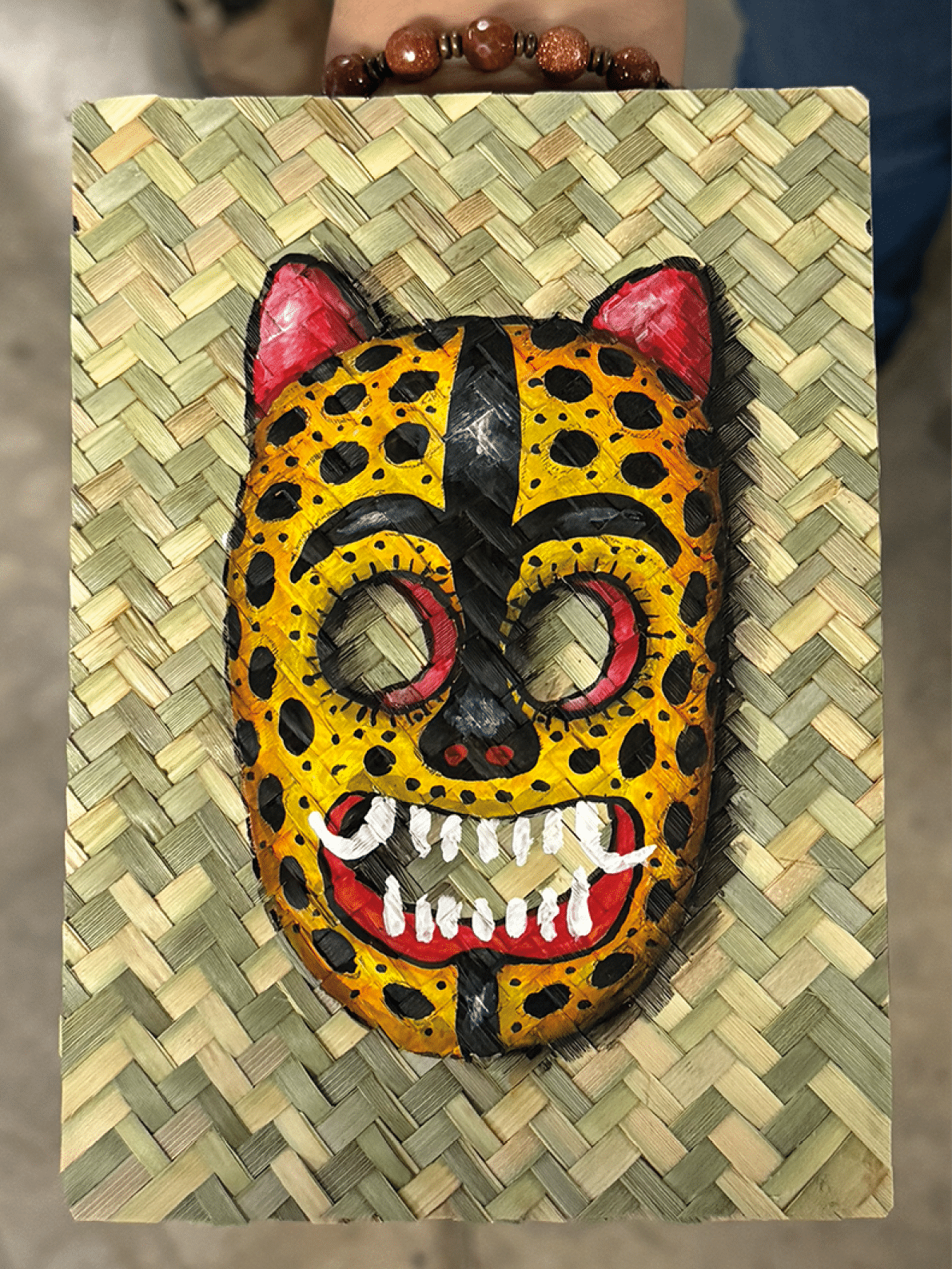 A hand holds a mask with a leopard face and red eyes. Contenido generado con IA